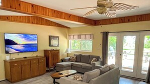 Ein Wohnzimmer mit einer Eckcouch, einem Fernseher und einem Holzkabinent.
