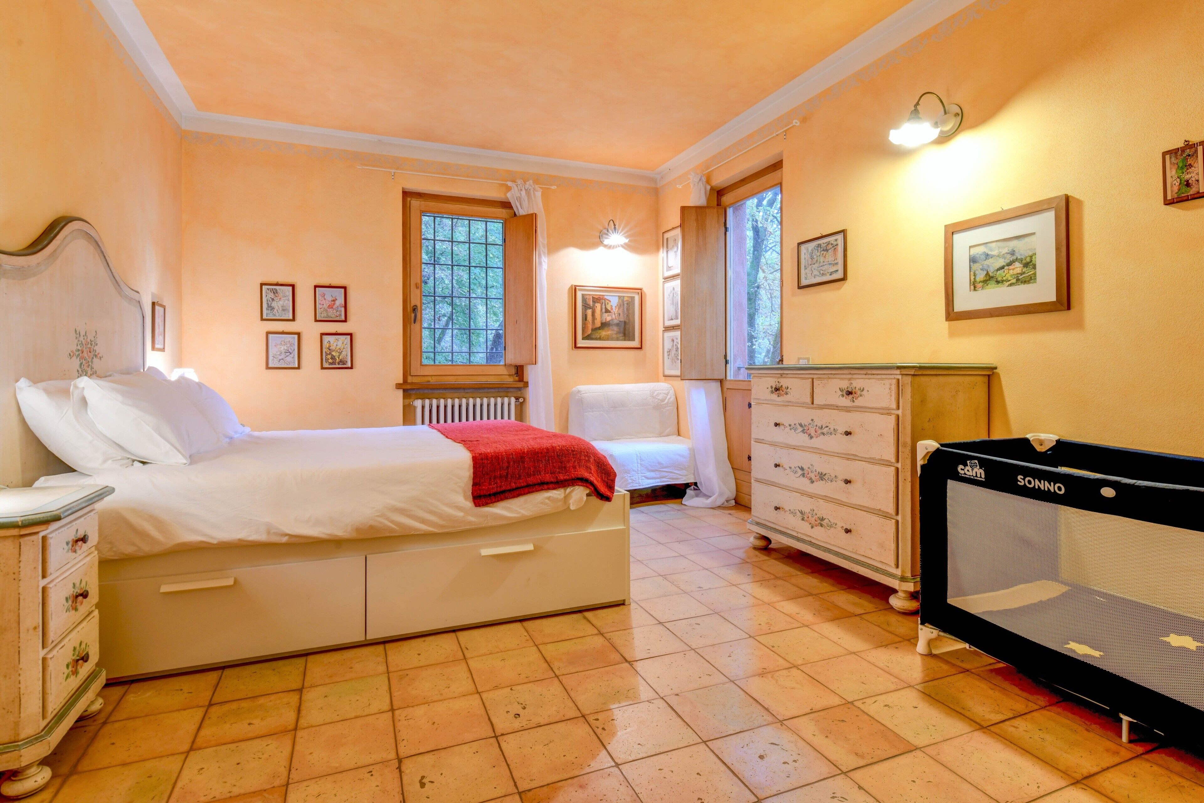 Een slaapkamer met een bed, een kapstok, een radiator en een ledikant.