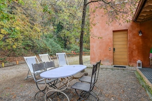 Un patio al aire libre con una mesa redonda y cuatro sillas, una puerta y un farol.