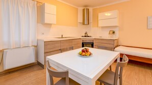 A compact kitchen with a dining table, a bench, and a fruit bowl.