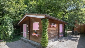 A small wooden cabin with pink accents, a door, and a window.