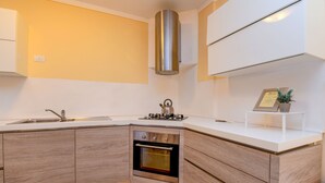 A modern kitchen with a built-in oven, stainless steel range hood, and a white countertop.