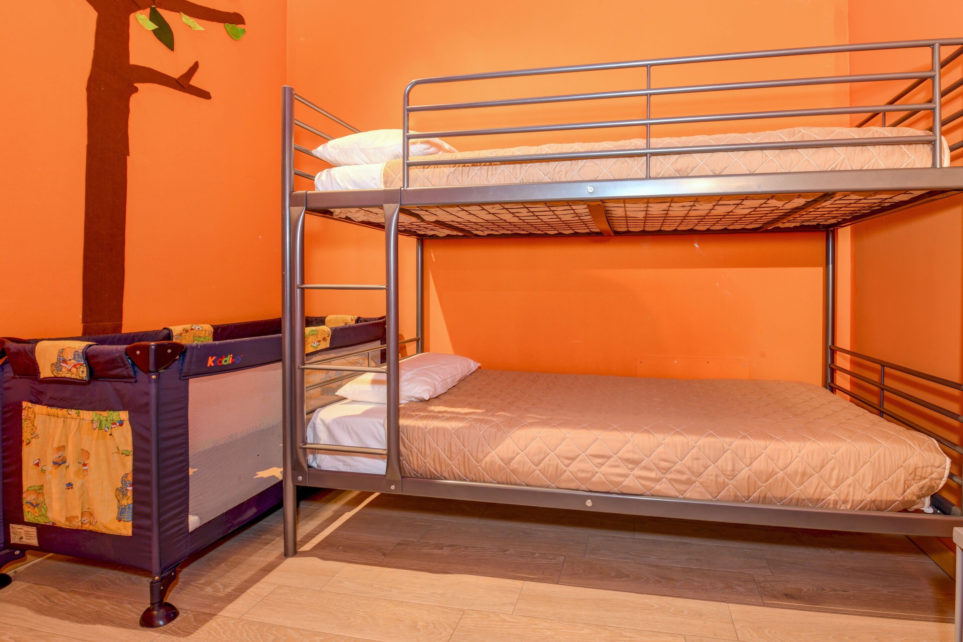 Un lit superposé avec un matelas et des oreillers, une petite table avec une chaise et un élément décoratif mural.