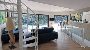 Um interior moderno com escada, sofá, área de jantar e cozinha.