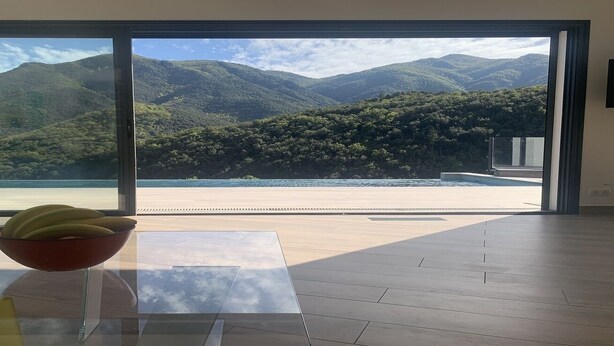 Quarto moderno com uma grande porta de vidro deslizante que dá para uma vista panorâmica das montanhas.