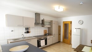 Une cuisine moderne avec des armoires blanches, une hotte de cuisinière en acier inoxydable, une planche à découper en bois et un comptoir noir.
