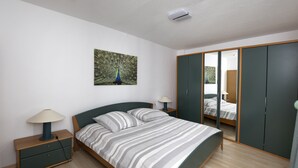 Une chambre à coucher comprenant un lit, des tables de chevet, un miroir et une armoire.