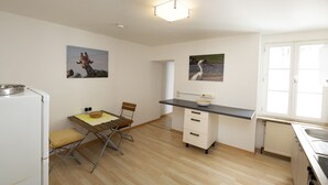 Une cuisine compacte comprenant une table à manger, un petit îlot central et deux tableaux accrochés au mur.