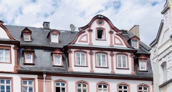 A row of traditional European-style buildings with symmetrical facades, dormer windows, and a central decorative element on the roof.