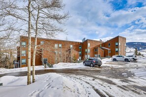 Un bâtiment moderne à la façade en briques, un parking enneigé et un ciel dégagé.