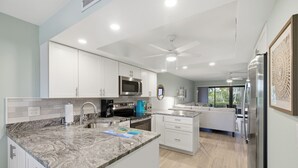 Eine moderne Küche mit weißen Schränken, einer Granitarbeitsplatte, einer eingebauten Mikrowelle und einem Deckenventilator.