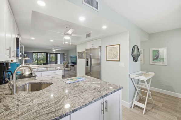 A modern kitchen with granite countertops, stainless steel appliances, and a white island.