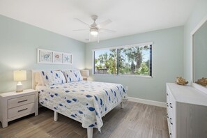 A bedroom with a bed, nightstands, a dresser, a ceiling fan, and a window with blinds.