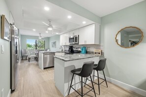 A modern kitchen with a central island, bar stools, and a dining area with chairs.