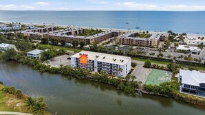 Ein Küstenhotel mit mehreren Gebäuden, einem Strand und einem Tennisplatz.