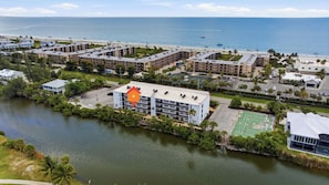 A coastal hotel with multiple buildings, a beach, and a tennis court. - 🌺Sandpebble 1E, 2 bed/2 bath & Ground-Level! Beach equipment provided! (Sanibel)