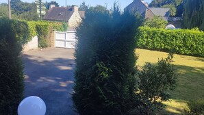 A stone staircase leading to a gated entrance with a clear view of a well-maintained garden and a residential area in the background. - Vacation home Côtes d'Armor in the commune of Quessoy (Quessoy)