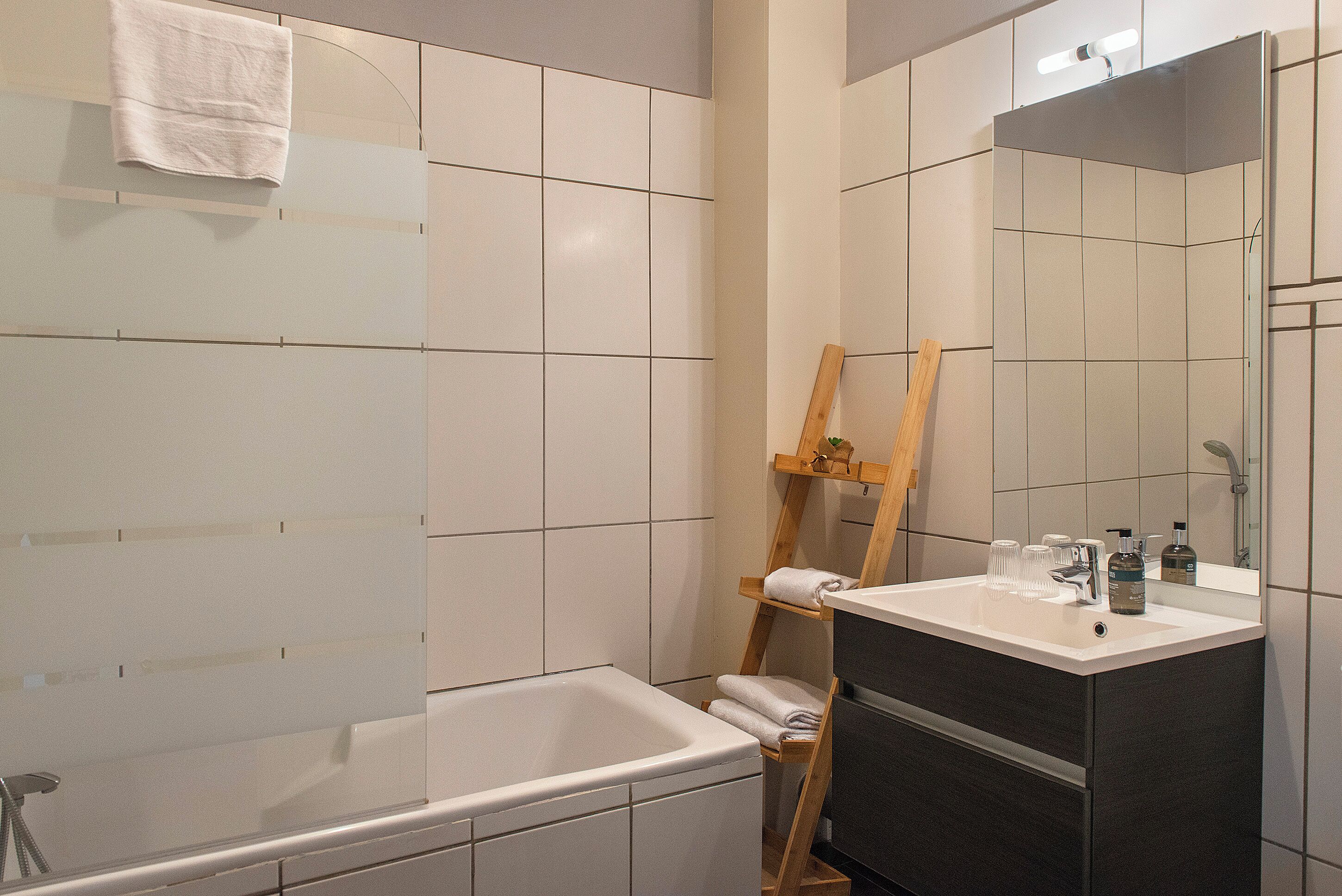A bathroom with a bathtub, a wooden easel, and a vanity with a mirror.