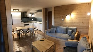 A modern kitchen with a dining area, a sofa, and a coffee table.
