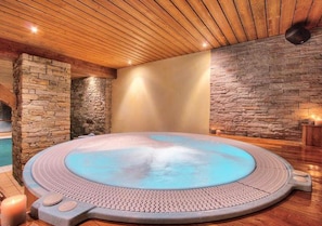 Un jacuzzi en una habitación con techo de madera y paredes de piedra.