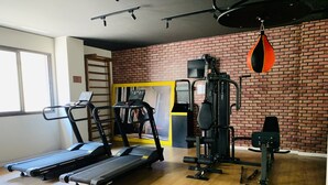 Een fitnessruimte met loopbanden, een krachttrainingapparaat en een bokszak.