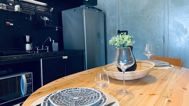 Een moderne keuken met een ingebouwde koelkast, koffiezetapparaat en magnetron. Een eettafel is gedekt met een vaas bloemen, wijnglazen en borden.