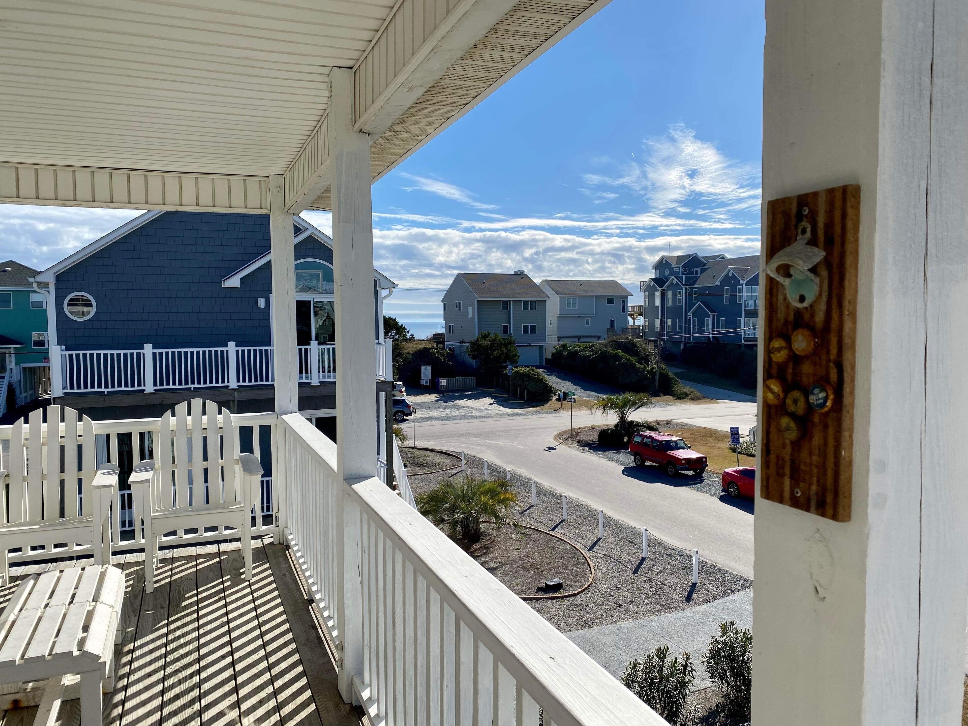 A balcony with a view of a residential area, including houses and a road.
