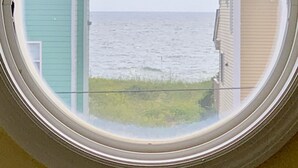 A circular window with a view of the sea and two houses. - Just steps to the beach! 🏝 Surf City Beach House (Surf City)
