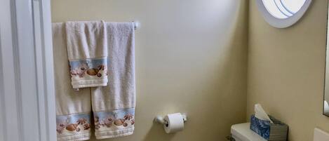 Un baño con inodoro, lavamanos y toallero con dos toallas.