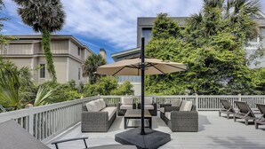 A deck with outdoor furniture, a central umbrella, and a view of surrounding buildings.