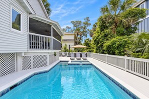 A swimming pool with a deck, surrounded by a white fence, and a covered outdoor seating area with chairs and an umbrella. - 4 Sea Hawk -Truly an island oasis, 4th row from the ocean. (Hilton Head Island)