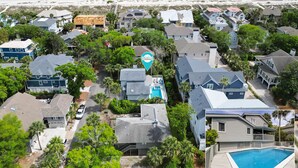 A residential area with houses, a swimming pool, and a beach in the background.