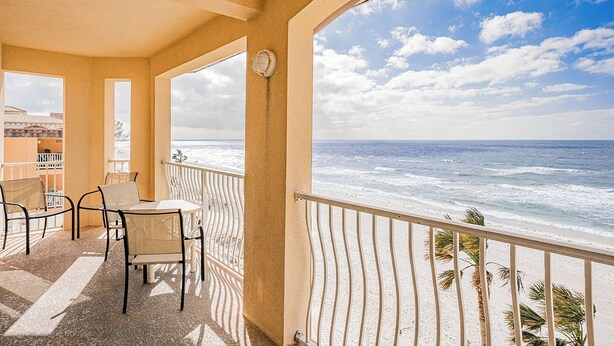 Un balcon avec vue sur l’océan, une table avec des chaises et une rambarde.