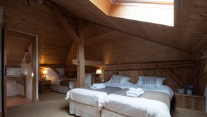 Een knus slaapkamer op zolder met een houten plafond, twee bedden, een kleine badkamer en een dakraam.