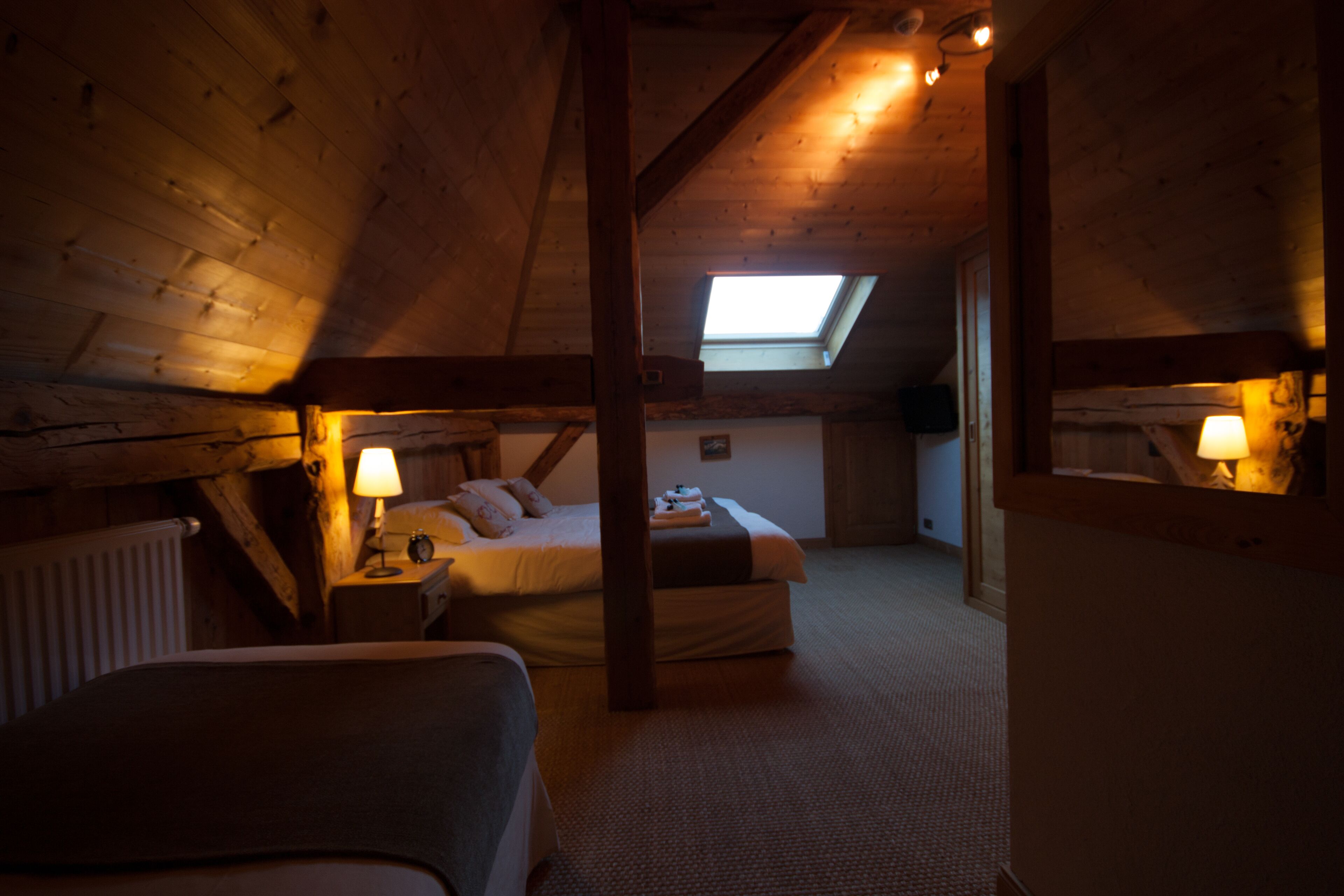 Un dormitorio acogedor en el ático con un tragaluz, una cama, una mesita de noche y una lámpara.