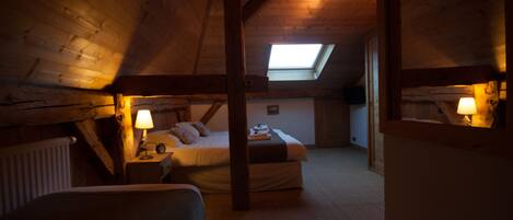 Un dormitorio acogedor en el ático con un tragaluz, una cama, una mesita de noche y una lámpara.