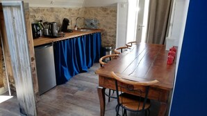 Una cocina compacta con una mesa y sillas de madera, un lavamanos y una cafetera.