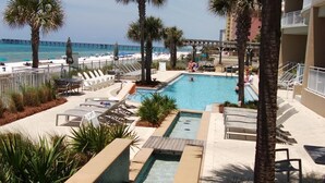 A pool area with lounge chairs, palm trees, and a view of the ocean. - Aqua 3br/3ba. 2 Master BD ocean view (Panama City Beach)