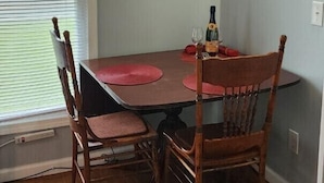 Un coin repas avec une table en bois, deux chaises et deux tableaux encadrés accrochés au mur.