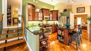 A modern kitchen with wooden cabinets, stainless steel appliances, and a central island with bar stools. - Riverside Retreat - Secluded exotic villa in the Rocky mountains (Waiparous Village)
