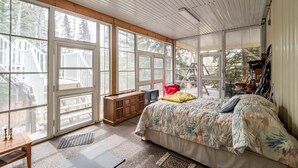A bedroom with large windows, a bed, a wooden cabinet, and a ladder outside. - Riverside Retreat - Secluded exotic villa in the Rocky mountains (Waiparous Village)