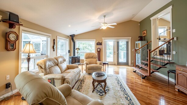 A spacious living room with a large sofa set, a fireplace, and a staircase leading to another level. - Riverside Retreat - Secluded exotic villa in the Rocky mountains (Waiparous Village)