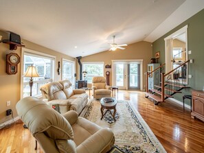 A spacious living room with a large sofa set, a fireplace, and a staircase leading to another level. - Riverside Retreat - Secluded exotic villa in the Rocky mountains (Waiparous Village)