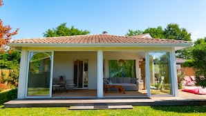 A modern house with a tiled roof, glass doors, and a patio with outdoor furniture.