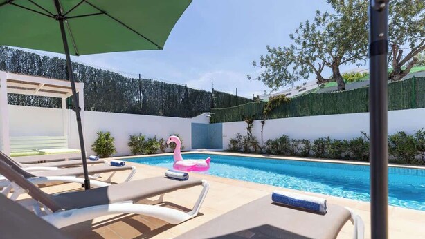 A pool area with lounge chairs and a pink flamingo float.