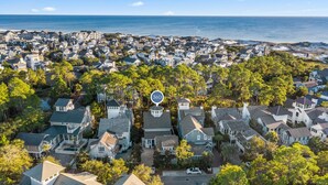 Vue aérienne d’une zone résidentielle côtière, avec des maisons, des arbres et une plage.