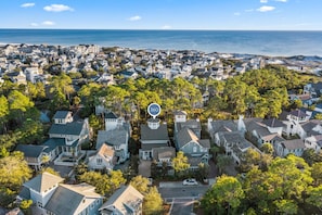 Vista aérea de una zona residencial costera con casas, árboles y una playa.
