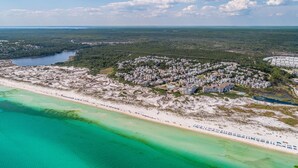 Vue aérienne d’une zone côtière comprenant une plage, un quartier résidentiel et une vaste étendue d’eau.