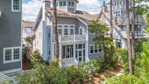 Une maison à deux étages dotée d’un balcon et d’une véranda qui fait le tour de la maison.
