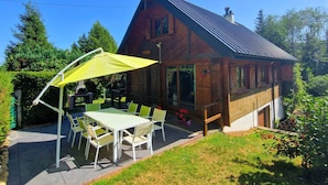 A wooden cabin with a sloped roof, a patio with a table and chairs, and a satellite dish. - Chalet de l'écureuil, petanque ground in the Vosges mountains near Gérardmer and Alsace (Anould)